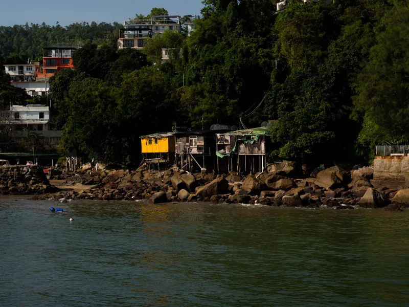 A bay with houses stacked up the green hillside above the water