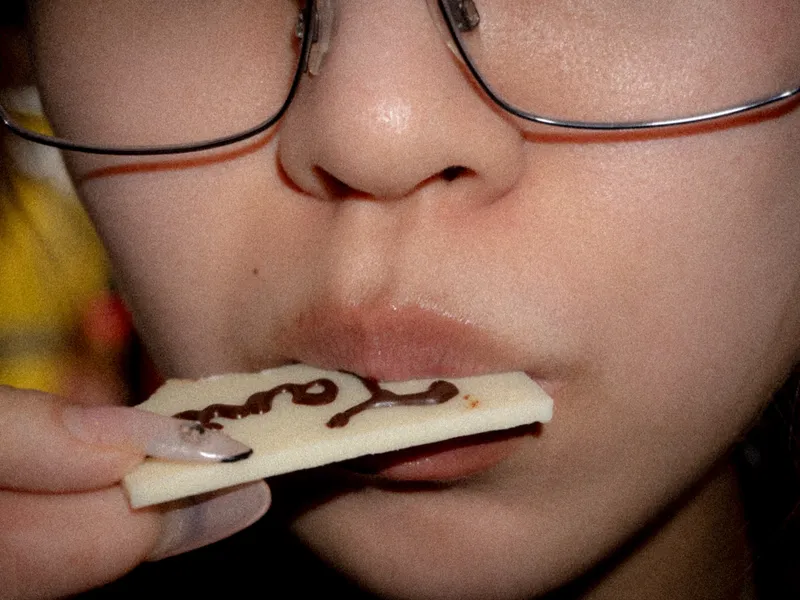 A close crop of a face, a tile held between the lips