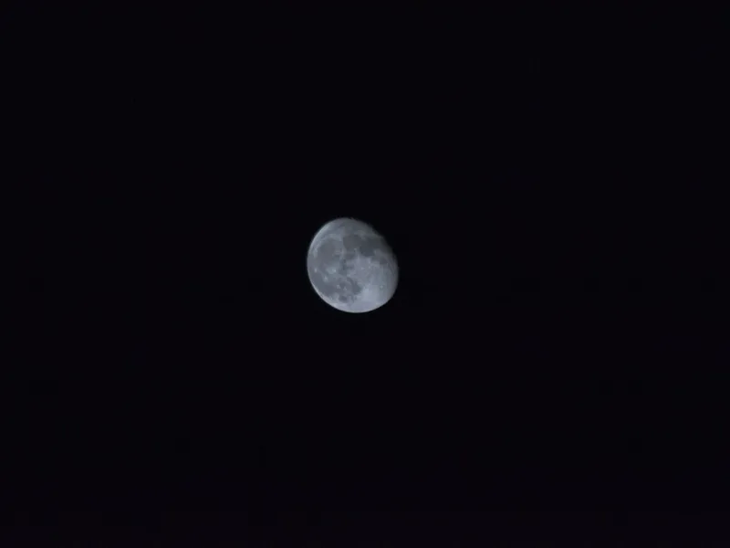 The moon bright and small in an otherwise black sky