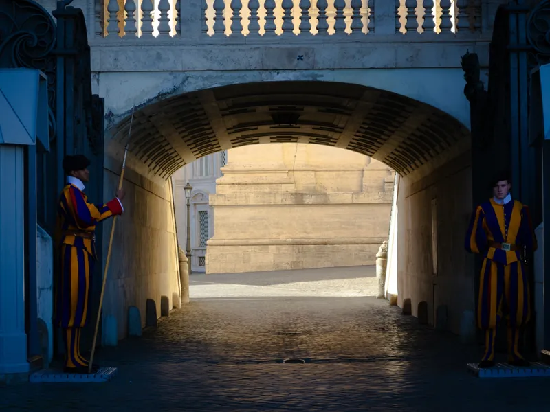 A vaulted passage lit blue, statues standing in the recesses either side